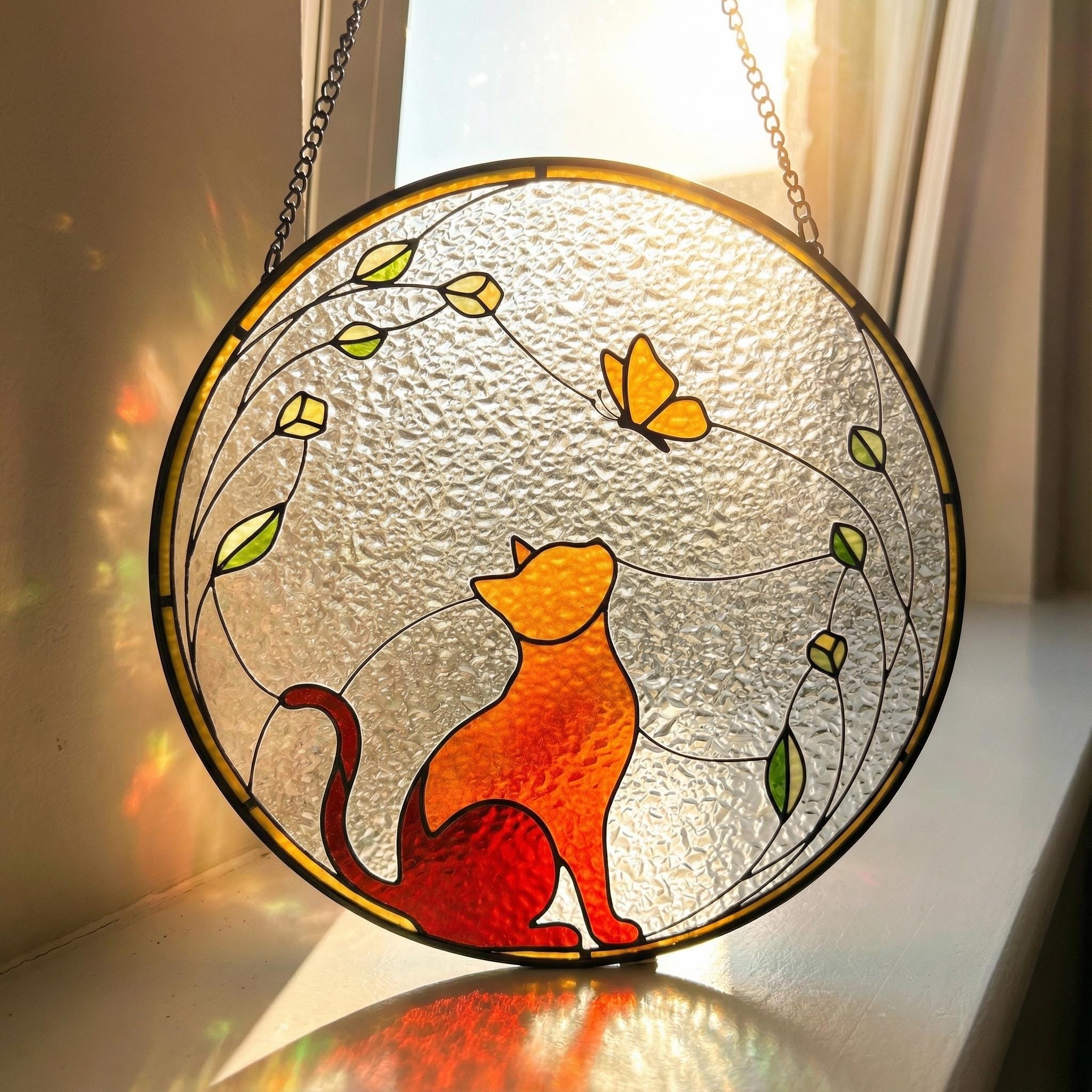 Stained glass suncatcher with a cat and butterfly design, hanging indoors.