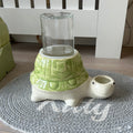Tortoise turtle-shaped anti gravity water bowl for no wet cat chins with a glass container on a textured rug.