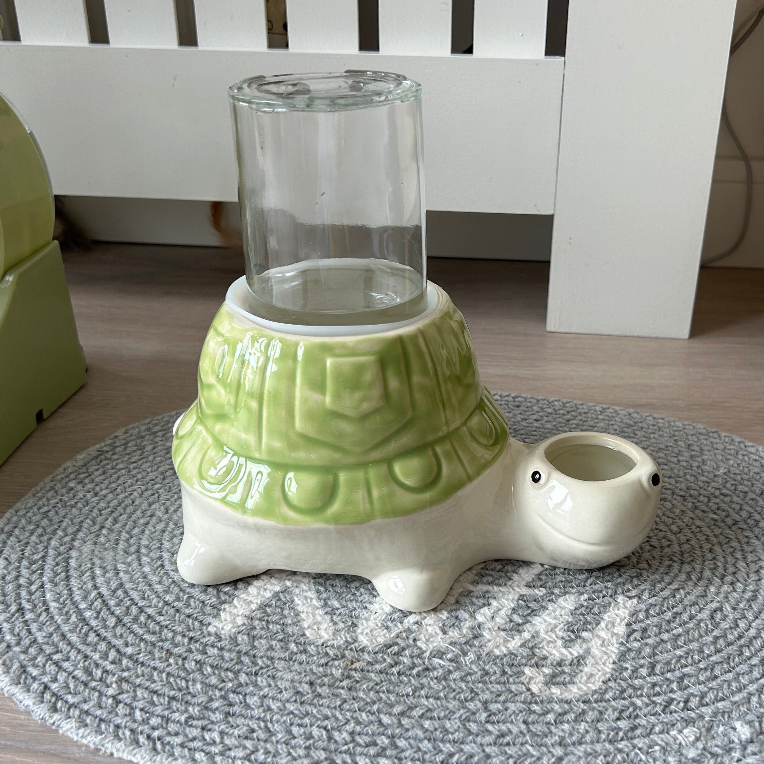 Tortoise turtle-shaped anti gravity water bowl for no wet cat chins with a glass container on a textured rug.