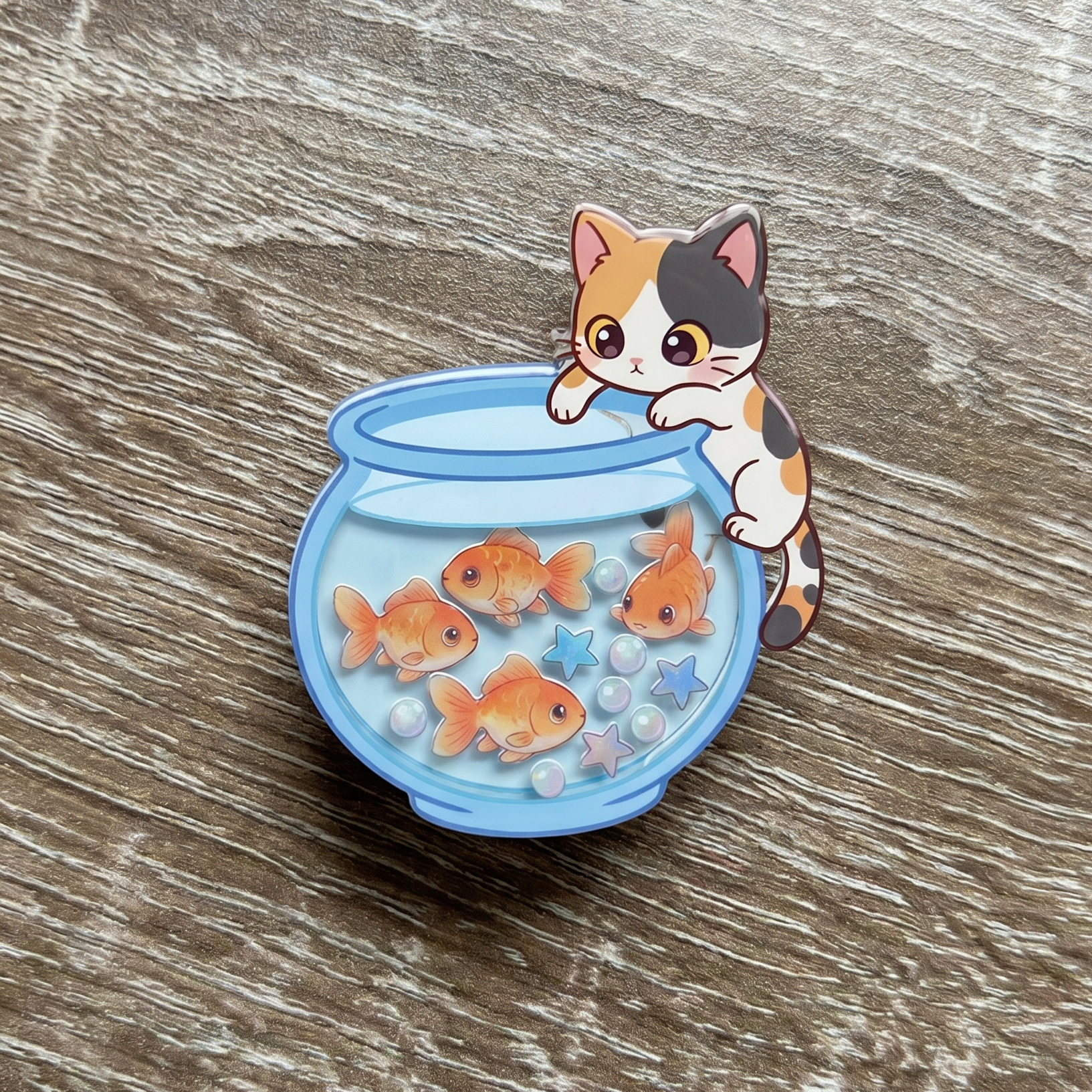 Cat-shaped expandable shaker phone grip with a fishbowl and goldfish on a wooden surface