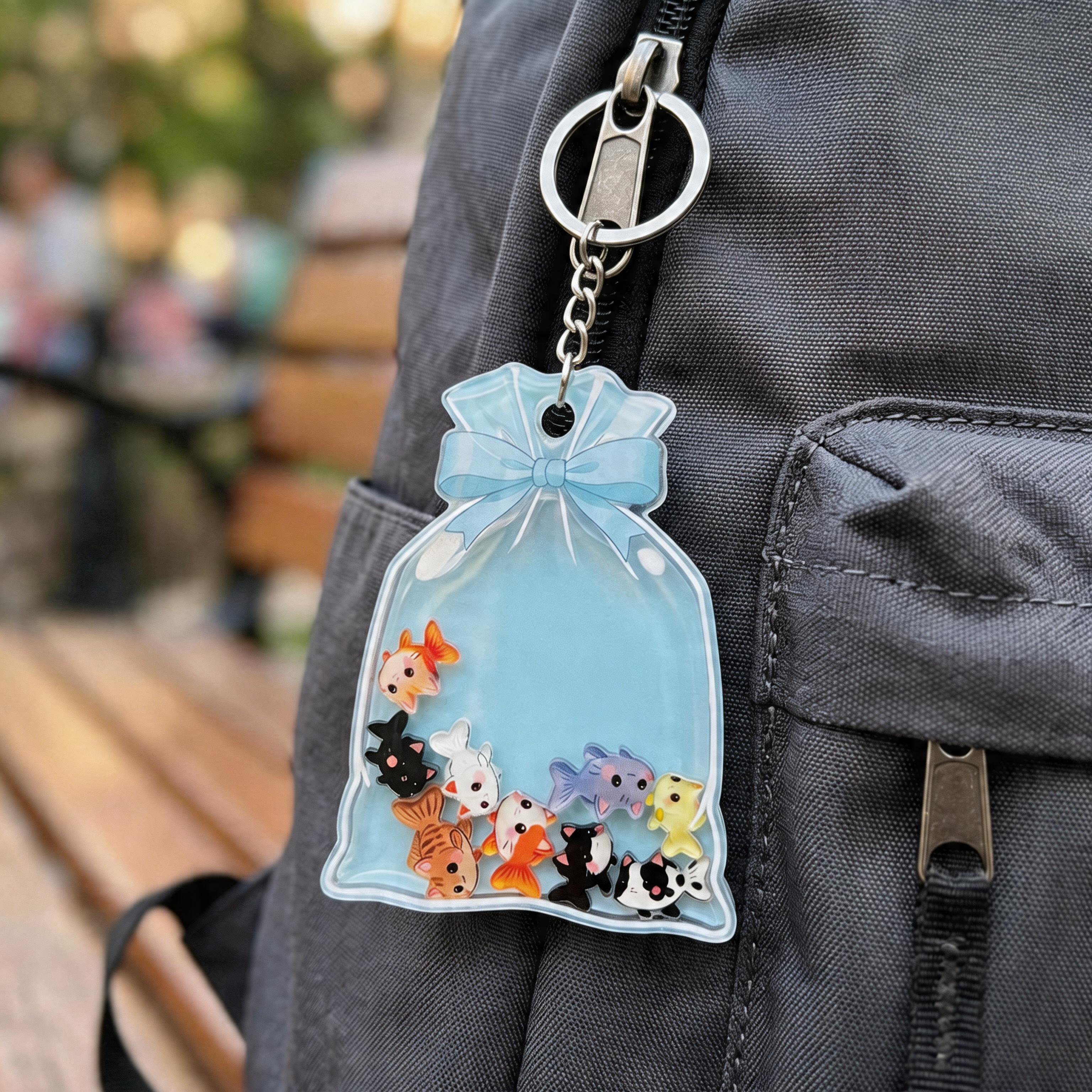 Keychain with kawaii cat fish figures in a blue bag attached to a backpack.