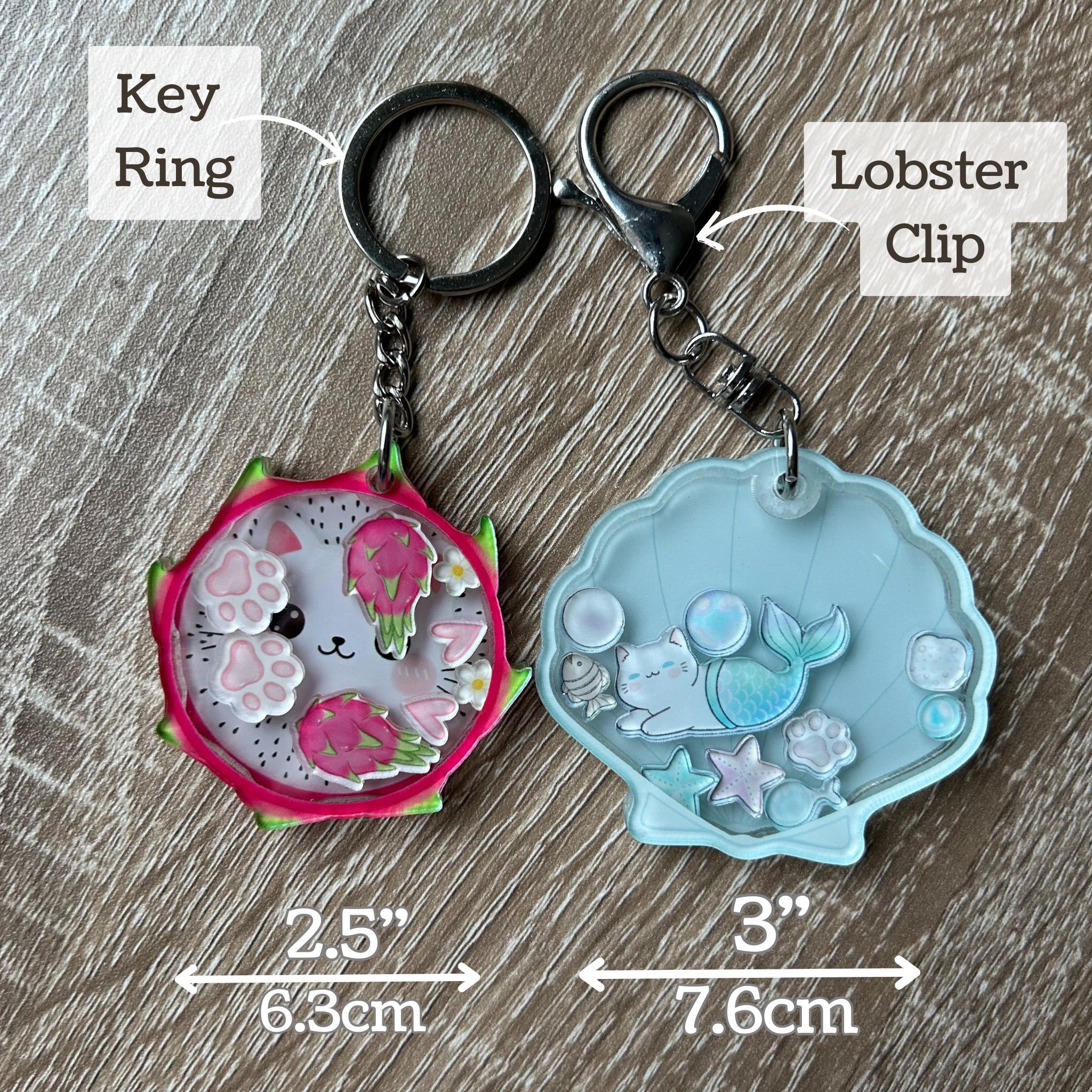 Two keychains with labels for key ring and lobster clip, on a wooden surface.