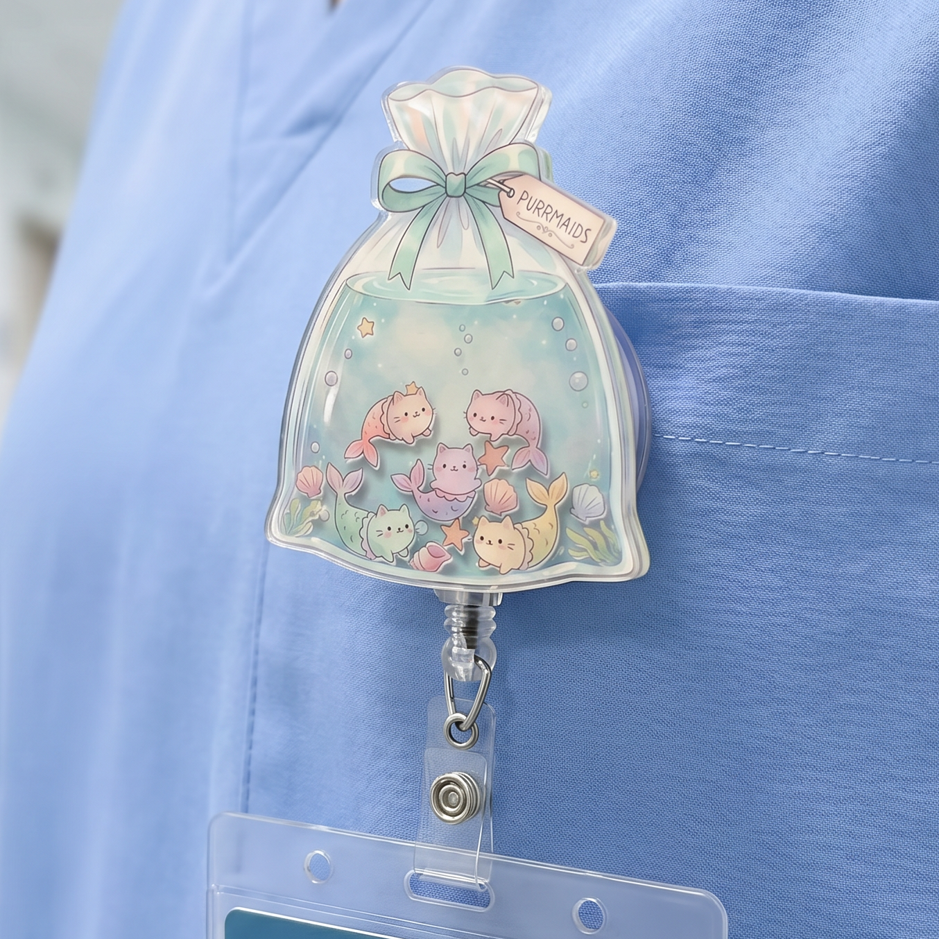Person wearing blue scrubs with a decorative bag of goldfish badge holder featuring cat mermaids / purrmaids.