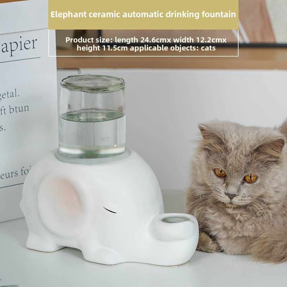 White ceramic elephant-shaped automatic drinking fountain with a cat sitting next to it.